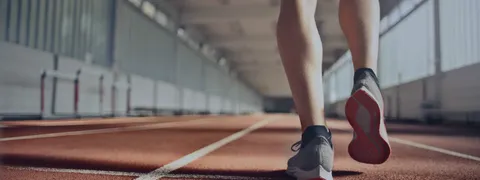 室内の陸上トラックを走る人の脚とシューズ